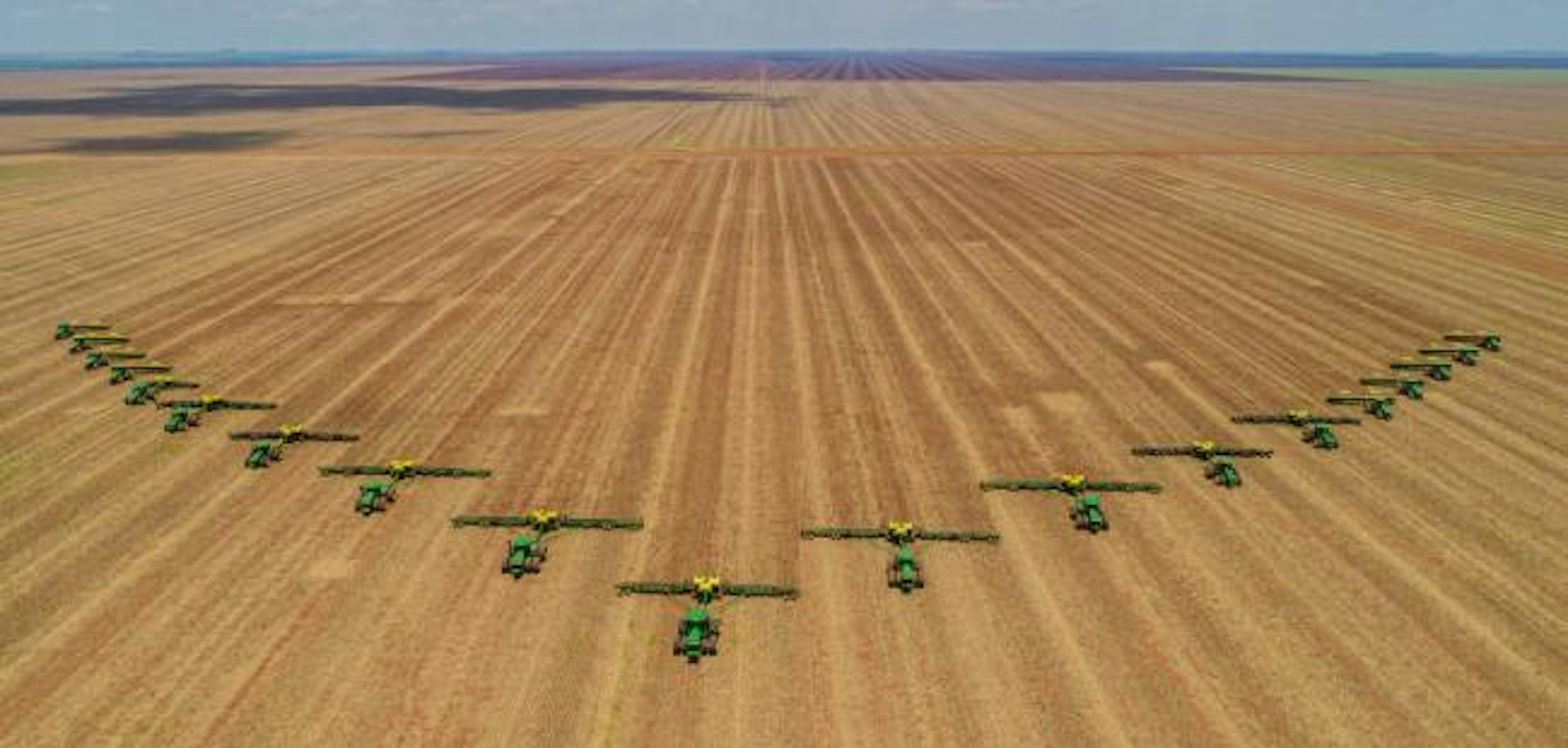 Aerial image, number of machines in arrow motion, front of tractors that prepare the land to sow in the field.